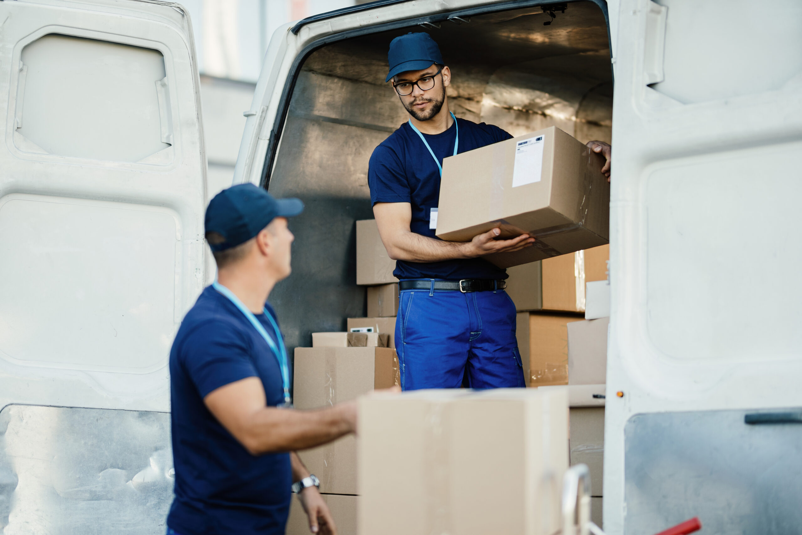 delivery man talking with a coworker while loading boxes in a va